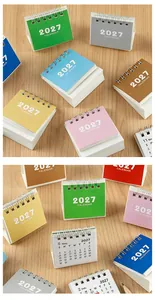 Colorful 2027 mini desk calendars with spiral binding on a light wooden background surface.