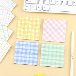 Assortiment de blocs-notes adhésifs à carreaux pastel sur un bureau de bureau épuré