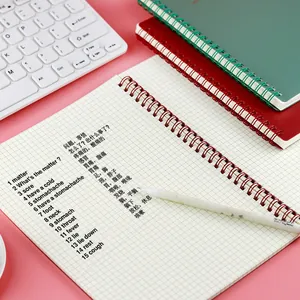 A5 spiraalnotitieboek met ruitjespagina's en Morandi-kleurige omslagen op een roze bureau