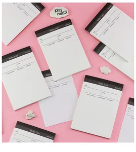 Vista detallada de blocs de notas blancos con encabezados negros sobre un fondo rosa