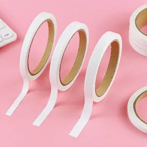 Set of white double-sided adhesive tape rolls for school and DIY crafts on pink background