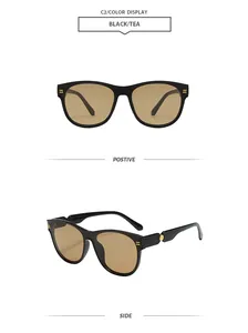 Vue détaillée des lunettes de soleil ovales noires avec verres thé et clous dorés.