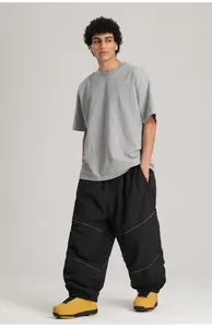 Lockere schwarze winddichte Skihose mit reflektierenden Streifen und gelben Stiefeln