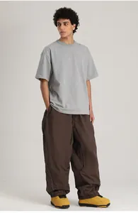 Vista de cuerpo completo de modelo con pantalones de esquí marrones y camiseta gris