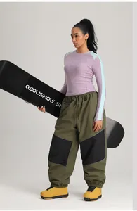 Detailansicht der wasserdichten olivgrünen Cargo-Skihose an einem Modell mit Snowboard