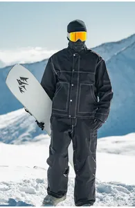Dettaglio a figura intera di un uomo in tuta da sci nera retrò in montagna innevata.
