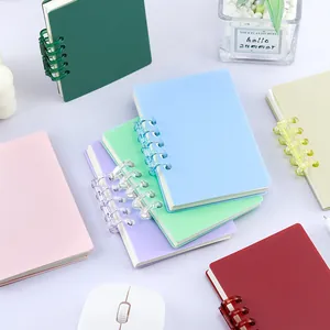 Carnets à spirales A7 pastel assortis dans un cadre de vie minimaliste avec une plante.