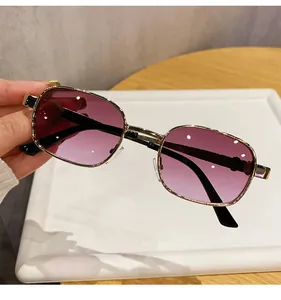 Gros plan de lunettes de soleil carrées vintage avec verres dégradés violets et monture dorée.