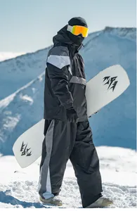 Modell im wasserdichten Colorblock-Skianzug-Set mit Snowboard in verschneiten Bergen