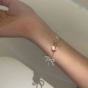 Elegante primo piano di un braccialetto di perle trasparenti con fiocco d'argento al polso