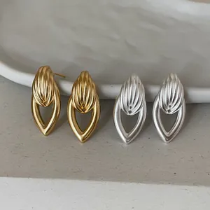 Vue détaillée de boucles d'oreilles clous géométriques en métal or et argent massif.