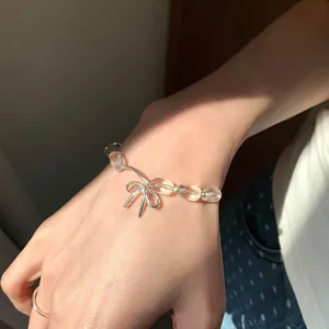 Vista dettagliata di un bracciale con perline trasparenti e un fiocco d'argento al polso