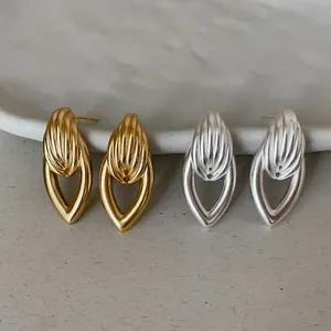 Détail de boucles d'oreilles minimalistes en métal doré et argenté en forme de goutte