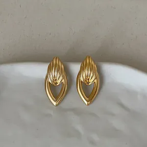 Gros plan détaillé de boucles d'oreilles dorées en forme de goutte creuse sur plat céramique