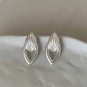 Gros plan sur des boucles d'oreilles clous géométriques argentées en forme de goutte creuse
