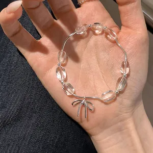 Dettaglio ravvicinato di un bracciale di perle trasparenti con ciondolo a fiocco argento