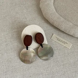 Detailed macro view of vintage round shell and wood spliced stud earrings for women