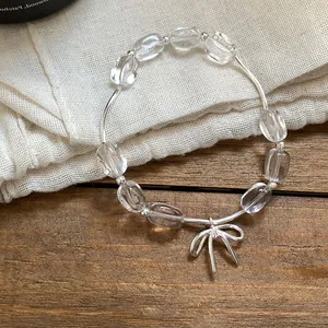 Vista dettagliata di un bracciale con perline trasparenti e un delicato ciondolo a fiocco.