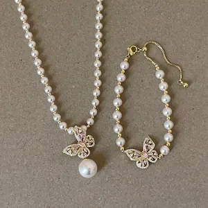 Elegante Detailansicht von Perlenhalskette und Armband mit rosa Schmetterlingsanhängern
