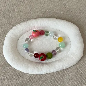 Gedetailleerd zicht op een zoete kleurrijke kralenarmband met schattige appelvormige bedels