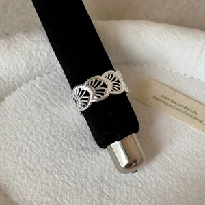 Detailed macro view of minimalist silver hollow scalloped design ring on black velvet