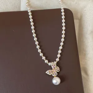 Elegante Detailansicht einer Perlenkette mit einem rosa Zirkon-Schmetterlingsanhänger.