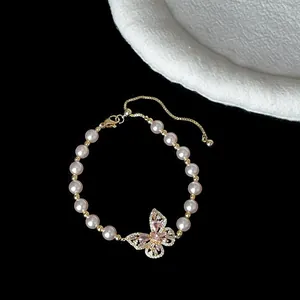 Detailansicht eines eleganten Perlenarmbands mit rosa Kristall-Schmetterlingsanhänger.