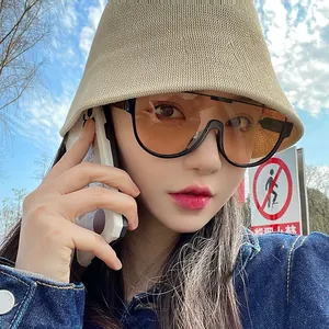 Close-up of oversized sunglasses with orange gradient lenses on a female model