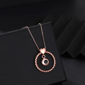 Close-up of rose gold heart and twisted circle projection necklace on jewelry box