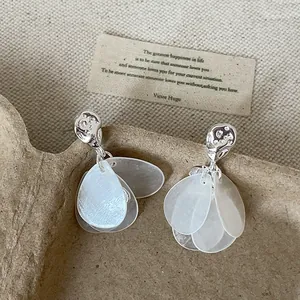 Primer plano de pendientes de plata con detalles de pétalos de concha blanca translúcida