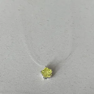 Détail d'un pendentif en zircone jaune en forme d'étoile sur une chaîne en fil de pêche.