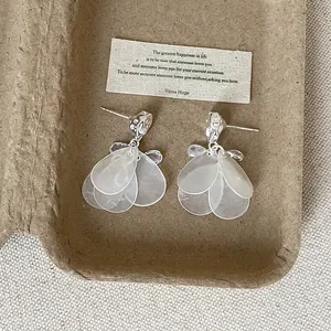 Primer plano de pendientes de plata con borlas de pétalos blancos translúcidos