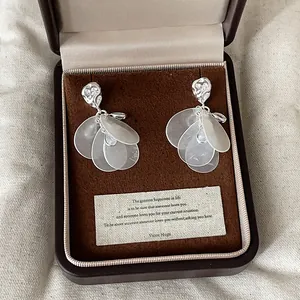Primer plano de elegantes pendientes de borla de concha con hoja de lágrima en caja.