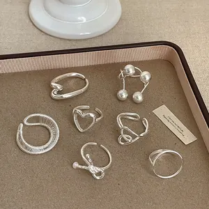 Sammlung silberner geometrischer Ringe mit Herz- und Schleifendetails auf einem Tablett