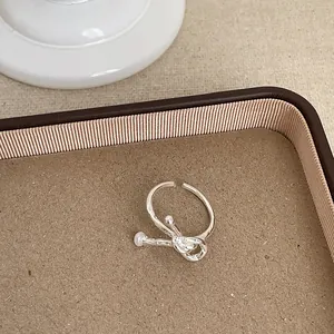 Detailansicht eines silbernen geometrischen Knotenrings in einer Schale