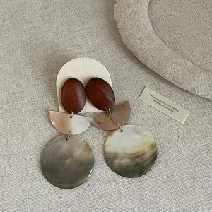 Detailed view of vintage round shell and wood patchwork earrings with natural textures