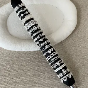 Various silver French-style lace hollow metal rings for women displayed on a rod.