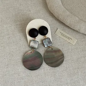 Detail view of retro geometric earrings with iridescent shell and wood textures