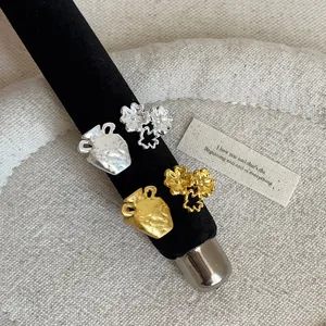 Close-up of French style textured amphora and floral metal rings in gold and silver