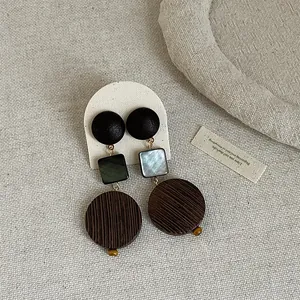 Detailed macro view showing textures of vintage geometric wood and shell splicing earrings