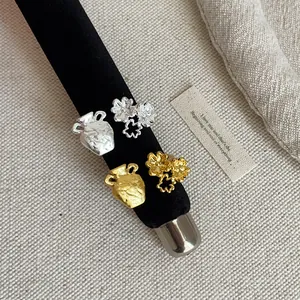 Macro detail of French style textured floral and vase shaped metal rings in gold and silver