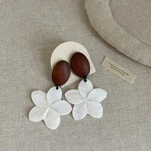 Detail view of vintage wood and white shell plumeria flower drop earrings