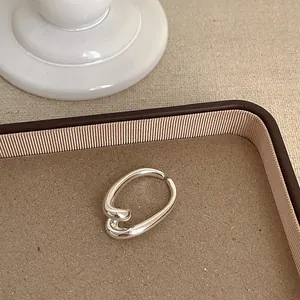 Nahaufnahme eines minimalistischen silbernen geometrischen Rings auf einem beigen Tablett