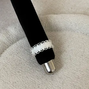 Close-up detail of a French style silver openwork lace ring on a black velvet stand.