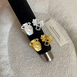 Detail of French style textured jar and flower metal rings on a black stand.