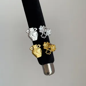 Close-up of textured gold and silver rings with flower and amphora designs