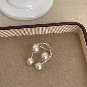 Detailaufnahme eines minimalistischen Silberrings mit vier Kugeln auf geometrischen Linien.