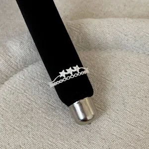 Close-up detail of a silver lace openwork ring featuring three sparkling stars
