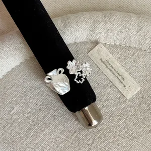 Detail of a textured silver-tone ring with a pot and flower charms on a black display rod.