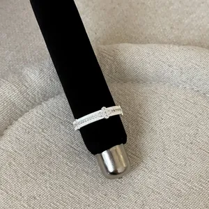 Close-up detail of a silver French lace hollow metal ring on a black display stand
